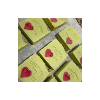 Rows of green Grumpy Heifer soap bars stamped with red hearts, handmade tallow soap by Tallowed Heifer